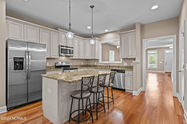 kitchen with a breakfast bar, a kitchen island, recessed lighting, stainless steel appliances, and light wood-style floors