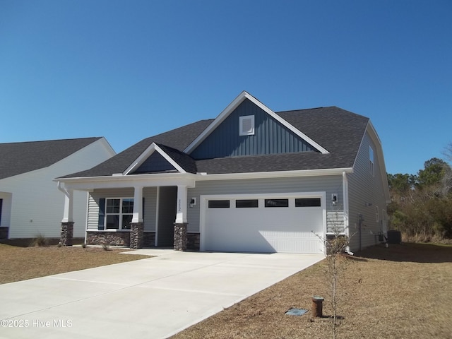 craftsman house with stone siding, an attached garage, driveway, and board and batten siding