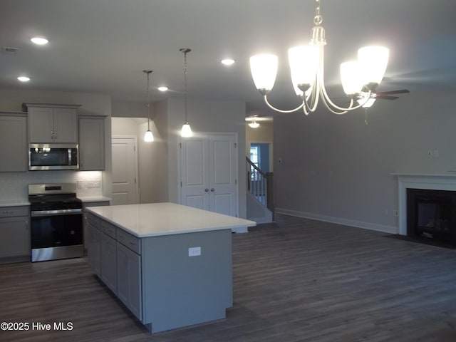 kitchen featuring a fireplace with flush hearth, appliances with stainless steel finishes, open floor plan, and gray cabinetry