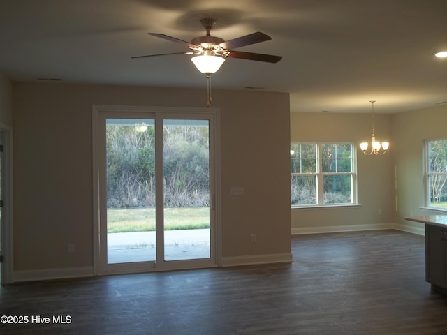 spare room featuring baseboards, wood finished floors, and ceiling fan with notable chandelier