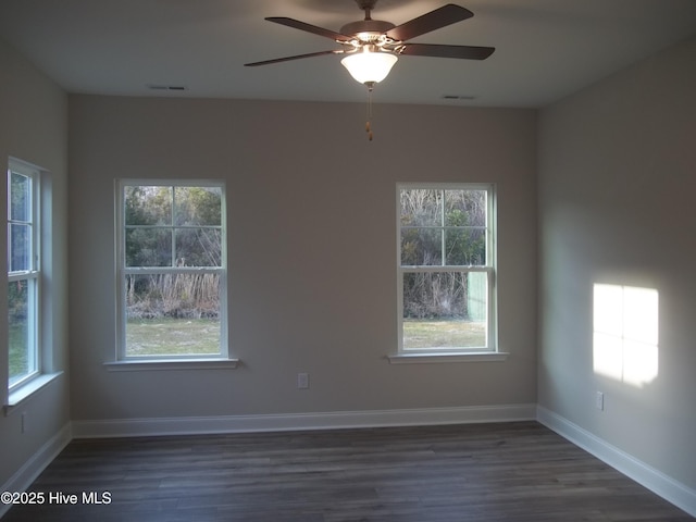 spare room with visible vents, baseboards, dark wood-type flooring, and ceiling fan