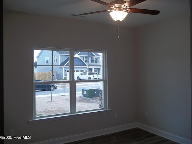 spare room featuring visible vents, baseboards, dark wood-type flooring, and ceiling fan