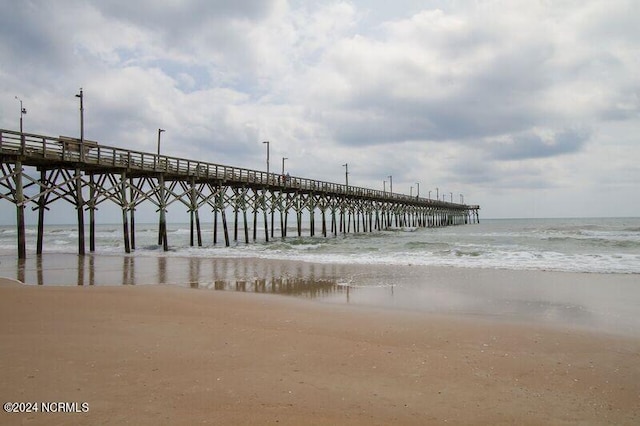 dock area featuring a pier, a water view, and a beach view