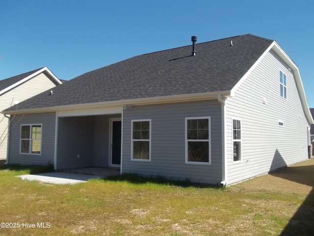 back of house featuring a yard, a patio area, and a shingled roof