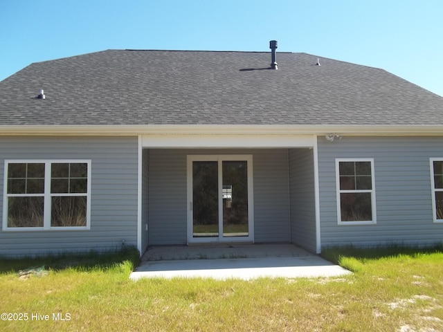 back of property with a patio, a shingled roof, and a yard