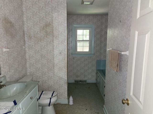 bathroom featuring toilet, visible vents, baseboards, vanity, and wallpapered walls