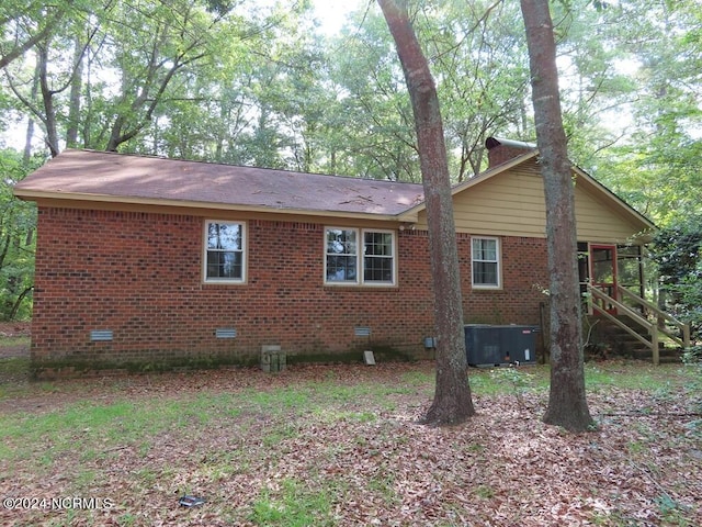 view of side of property featuring cooling unit, crawl space, and brick siding