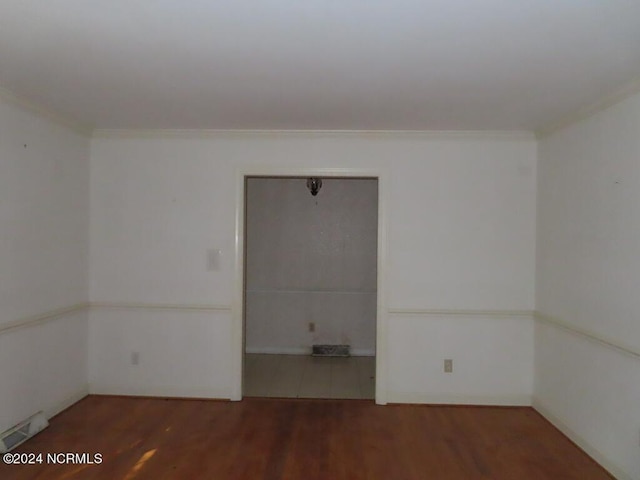 empty room with crown molding, visible vents, and wood finished floors