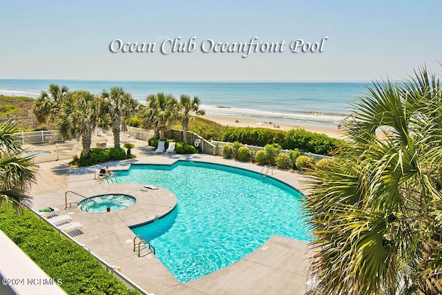 view of swimming pool featuring a patio area, a beach view, a hot tub, and a water view