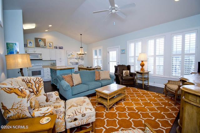 living room with ceiling fan with notable chandelier, dark hardwood / wood-style floors, vaulted ceiling, and a wealth of natural light