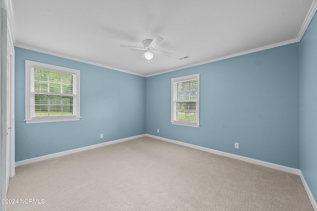 carpeted spare room featuring ceiling fan, crown molding, and plenty of natural light