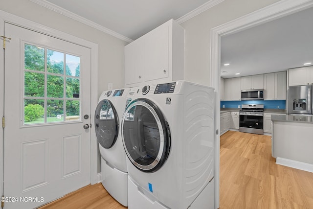 washroom with ornamental molding, light hardwood / wood-style flooring, washing machine and clothes dryer, and cabinets