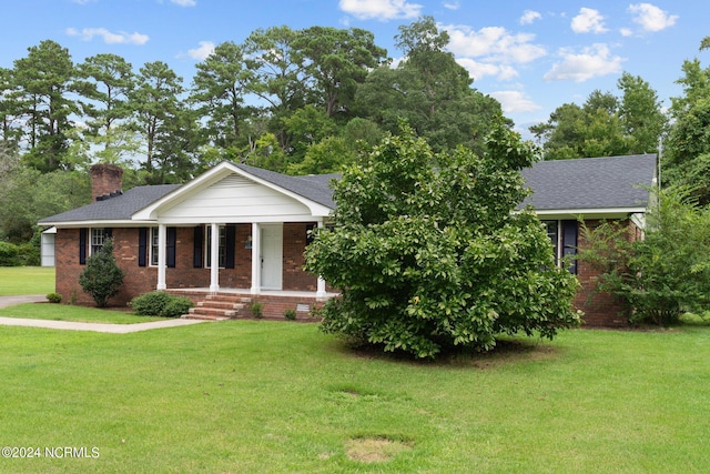 ranch-style home with brick siding, a shingled roof, a chimney, covered porch, and a front yard