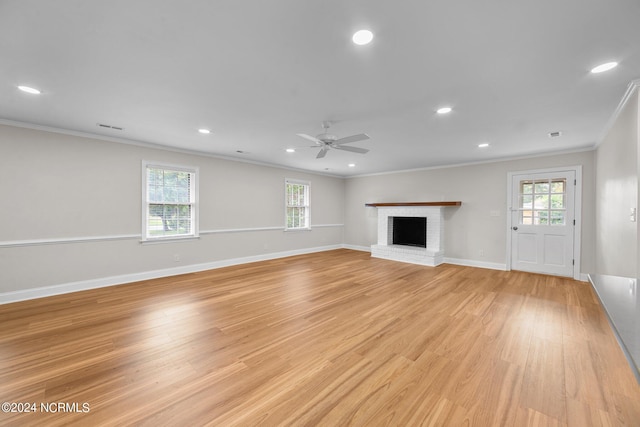 unfurnished living room featuring crown molding, a fireplace, light wood-type flooring, and ceiling fan