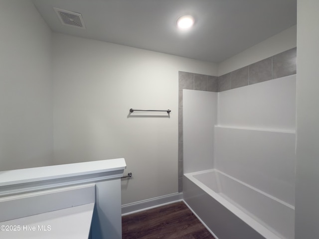 bathroom featuring  shower combination, wood finished floors, visible vents, and baseboards