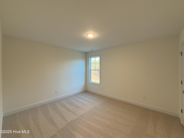 spare room with light colored carpet and baseboards