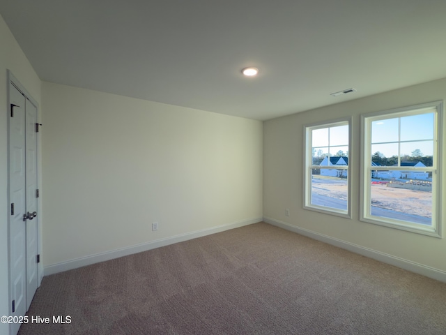 carpeted empty room with visible vents and baseboards