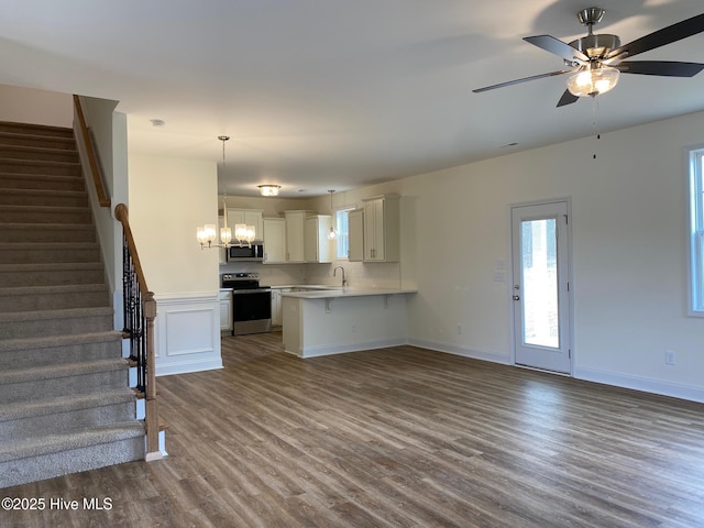 kitchen featuring stainless steel appliances, dark wood-type flooring, a peninsula, open floor plan, and light countertops