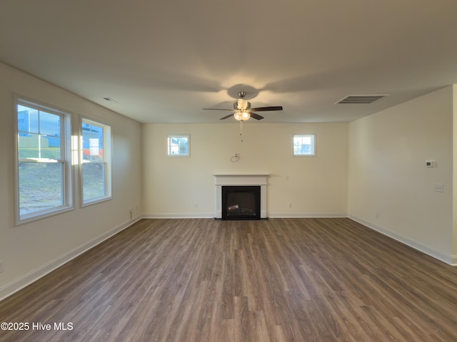 unfurnished living room featuring baseboards, a fireplace with flush hearth, and wood finished floors