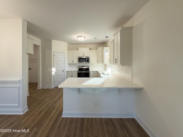 kitchen with a peninsula, a sink, light countertops, appliances with stainless steel finishes, and tasteful backsplash