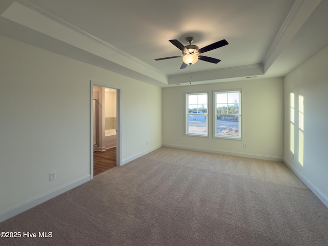 unfurnished room with baseboards, a tray ceiling, and ornamental molding