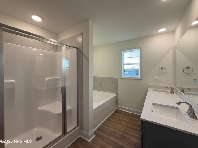 bathroom featuring a bath, wood finished floors, a stall shower, and a sink