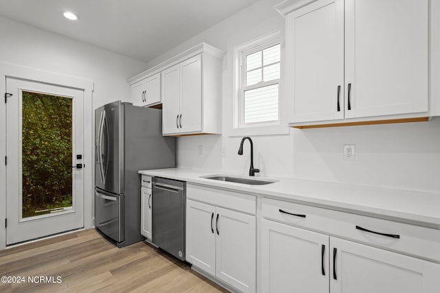 kitchen with white cabinets, light hardwood / wood-style floors, stainless steel appliances, and sink