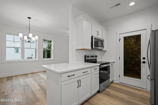 kitchen with appliances with stainless steel finishes, white cabinetry, light hardwood / wood-style flooring, and a notable chandelier