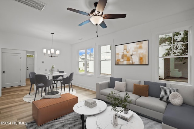 living room with light wood-type flooring, ceiling fan with notable chandelier, and a wealth of natural light