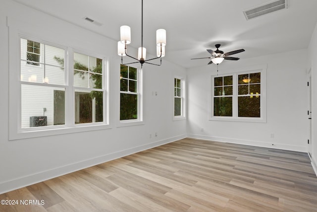 unfurnished dining area with ceiling fan with notable chandelier and light wood-type flooring