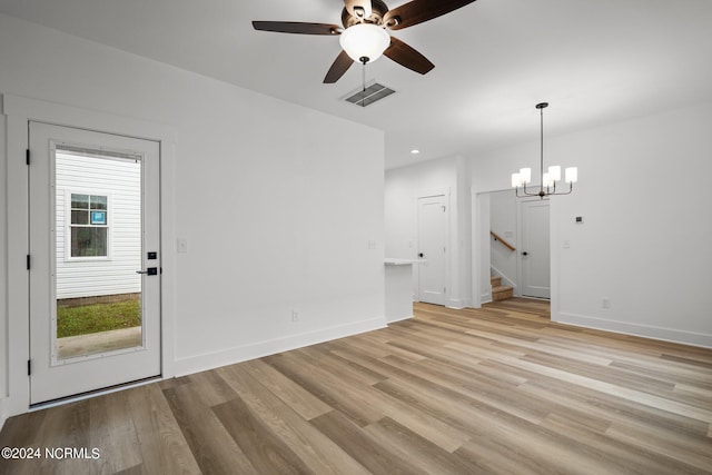 unfurnished living room featuring ceiling fan with notable chandelier and light hardwood / wood-style flooring