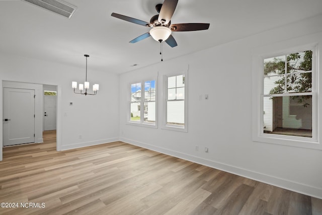 unfurnished room featuring light hardwood / wood-style flooring, ceiling fan with notable chandelier, and plenty of natural light