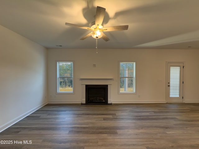 unfurnished living room with ceiling fan, plenty of natural light, and dark hardwood / wood-style flooring