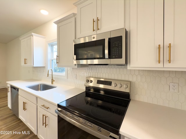 kitchen featuring stainless steel appliances, white cabinetry, sink, and backsplash