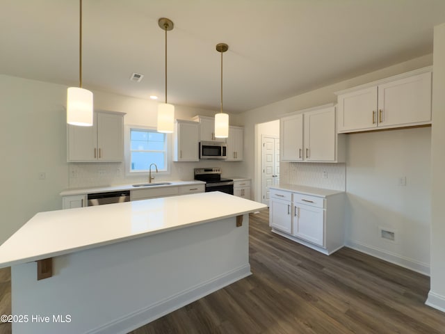 kitchen with a kitchen island, pendant lighting, sink, white cabinets, and stainless steel appliances