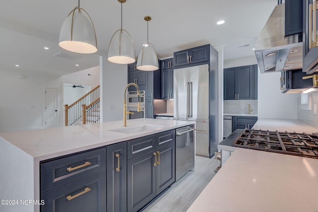 kitchen featuring light stone counters, light hardwood / wood-style flooring, an island with sink, pendant lighting, and high quality fridge