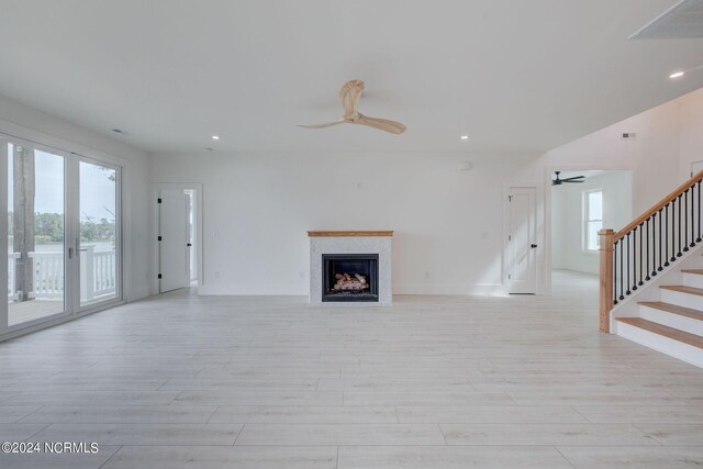 unfurnished living room with ceiling fan, light hardwood / wood-style flooring, and french doors