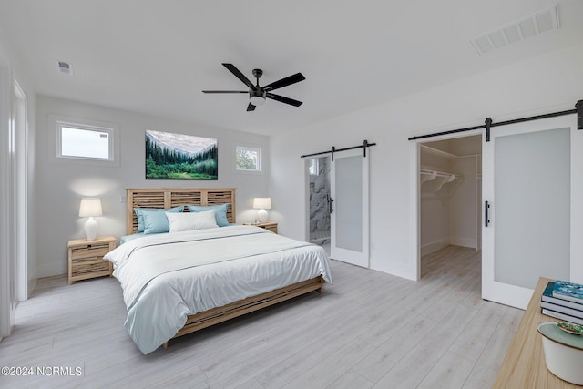 13 E Cannon Cv, Hampstead, NC 28443 - bedroom with visible vents, a barn door, light wood-style flooring, and a spacious closet