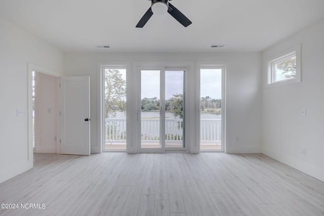 spare room with ceiling fan, a water view, and light hardwood / wood-style floors