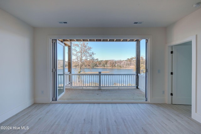 unfurnished room featuring a wealth of natural light, light hardwood / wood-style flooring, and a water view