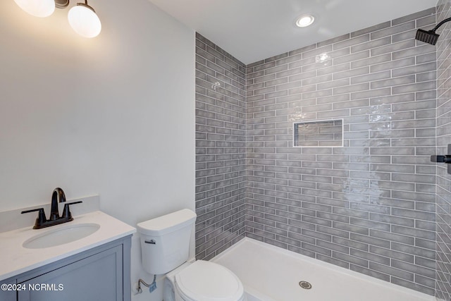 bathroom with tiled shower, vanity, and toilet