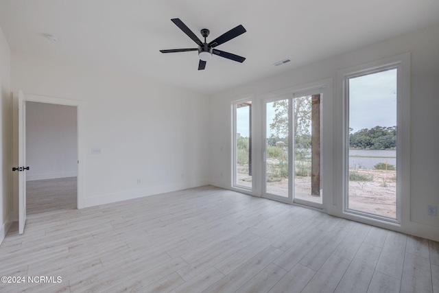 empty room featuring ceiling fan, a water view, and light hardwood / wood-style flooring