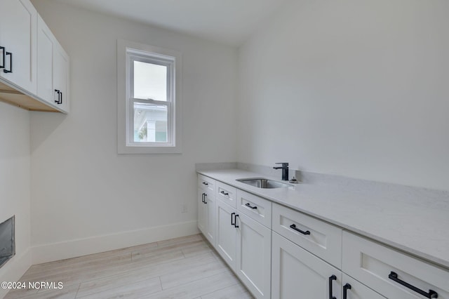 laundry area with light hardwood / wood-style floors and sink