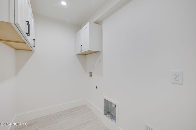 washroom featuring hookup for an electric dryer, washer hookup, cabinets, and light hardwood / wood-style flooring