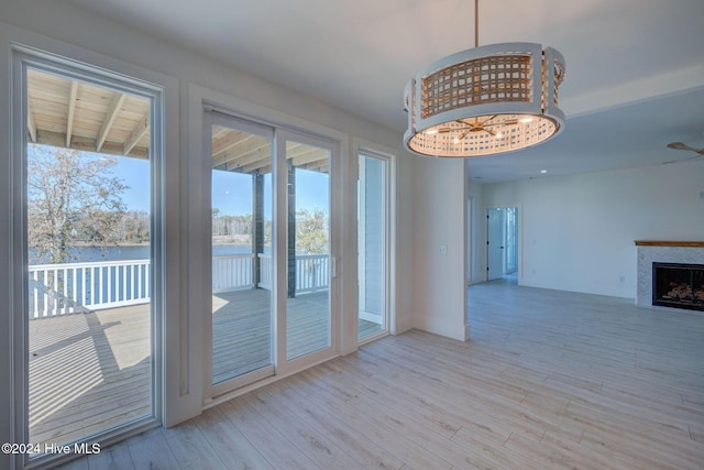 doorway with light hardwood / wood-style floors, ceiling fan, and a water view