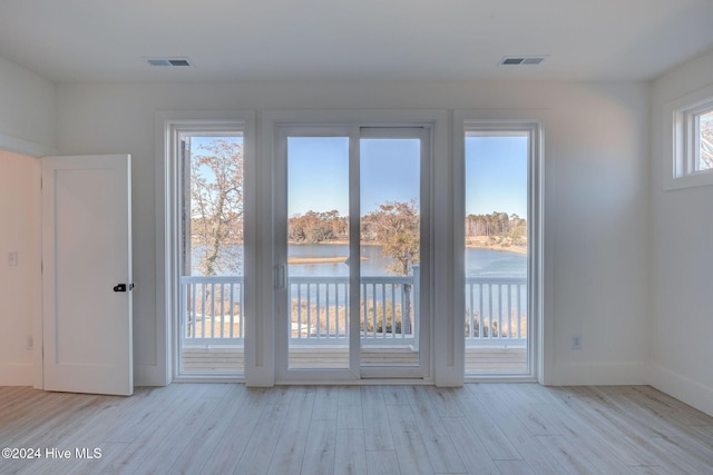 doorway to outside with light hardwood / wood-style flooring and a water view