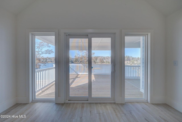 doorway featuring lofted ceiling, a water view, and light wood-type flooring