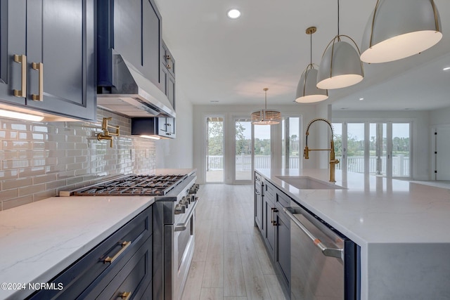 kitchen featuring light stone counters, stainless steel appliances, sink, decorative light fixtures, and light hardwood / wood-style flooring