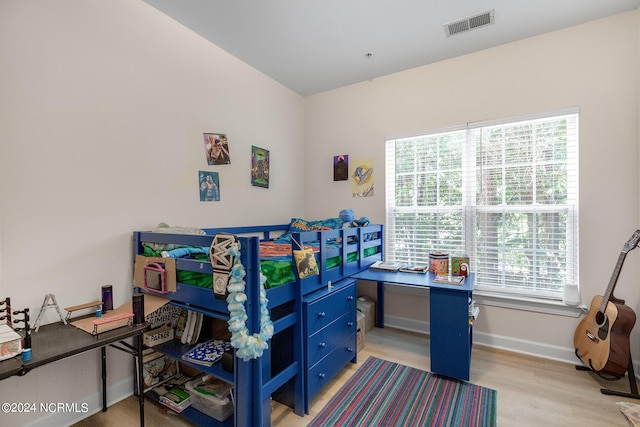 bedroom with multiple windows, wood finished floors, visible vents, and baseboards