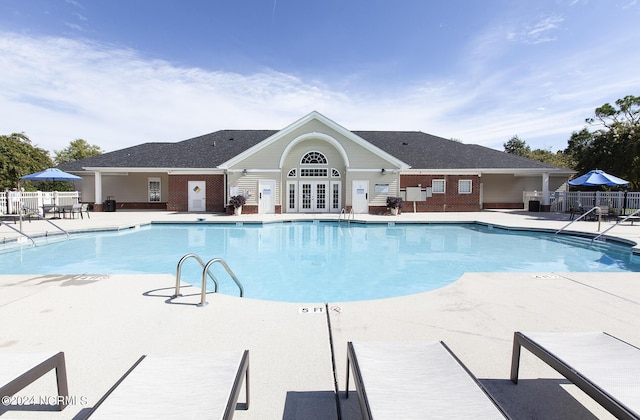 community pool featuring french doors, a patio area, and fence